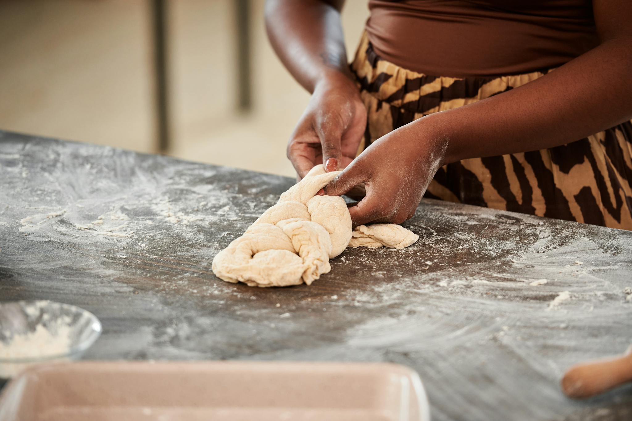 Close-up of hands kneading dough with flour on a kitchen surface, showcasing a baking process.